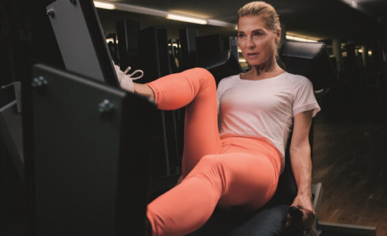 Eine Frau sitzt auf einem Fitnessgerät im Fitnessstudio und konzentriert sich auf ihr Training.