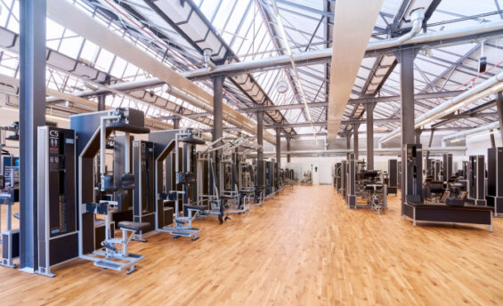 Ein Fitnessstudio mit einem großen Raum, der mit zahlreichen Trainingsgeräten ausgestattet ist.