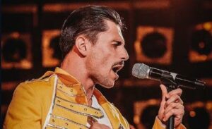 Ein Mann in einer gelben Jacke singt in ein Mikrofon.