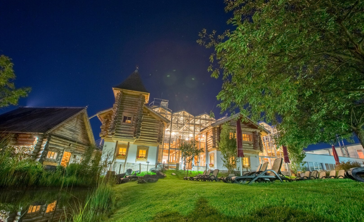 Nachtansicht eines großen Hauses neben einem Teich, beleuchtet von sanften Lichtern und umgeben von Stille.