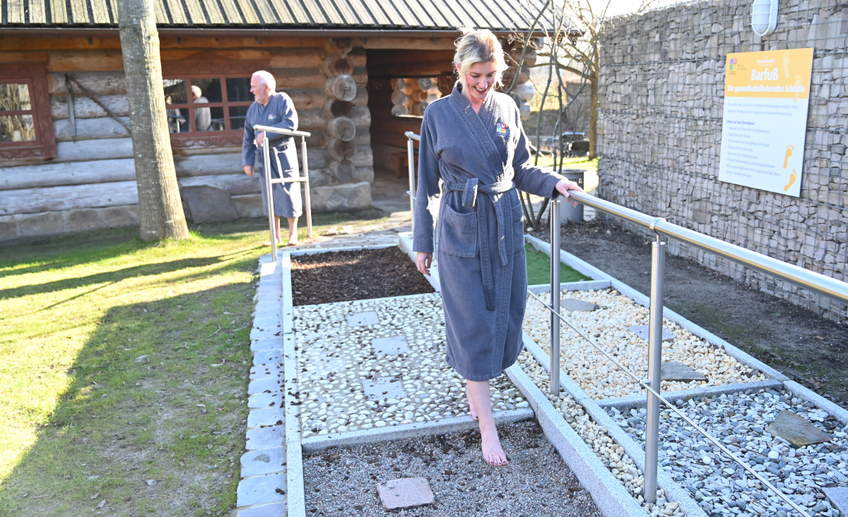 Eine Frau in einem Bademantel geht entspannt auf einem Weg entlang.