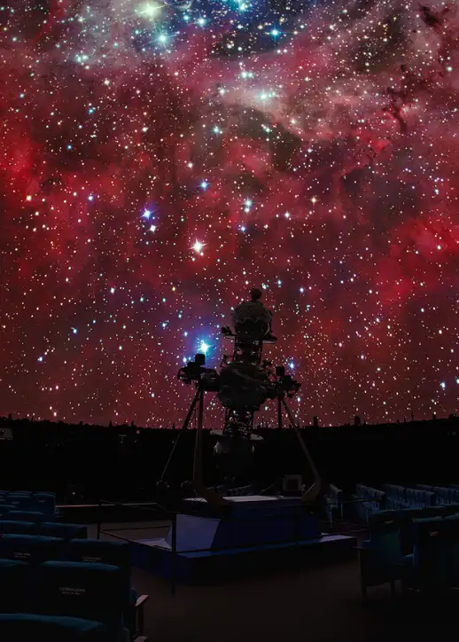 Ein Teleskop steht inmitten eines Sternenfeldes im Planetarium Berlin, umgeben von funkelnden Sternen.