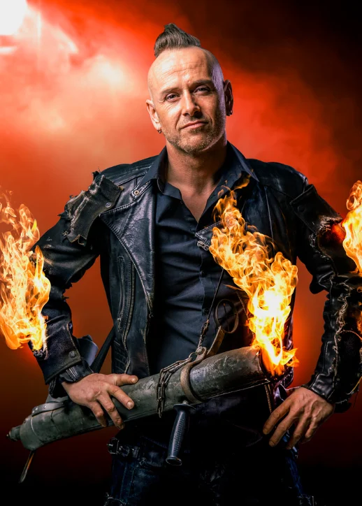 Ein Mann, der einen Feuerstock und ein Messer hält, in der gruseligen Kulisse des Zirkus des Horrors in Berlin.