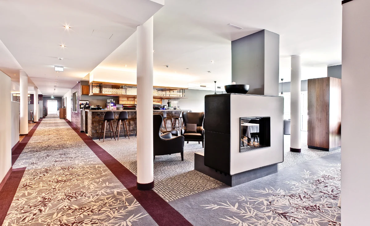 Moderner Hotel-Lobby mit einem gemütlichen Kamin und einer stilvollen Bar im Hintergrund.