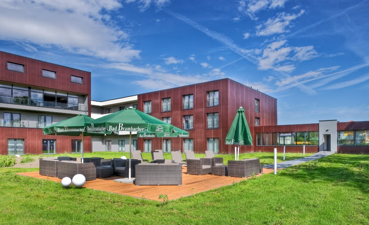 Gepflegter grüner Rasen, umgeben von einer Holzterrasse mit Sitzgelegenheiten.