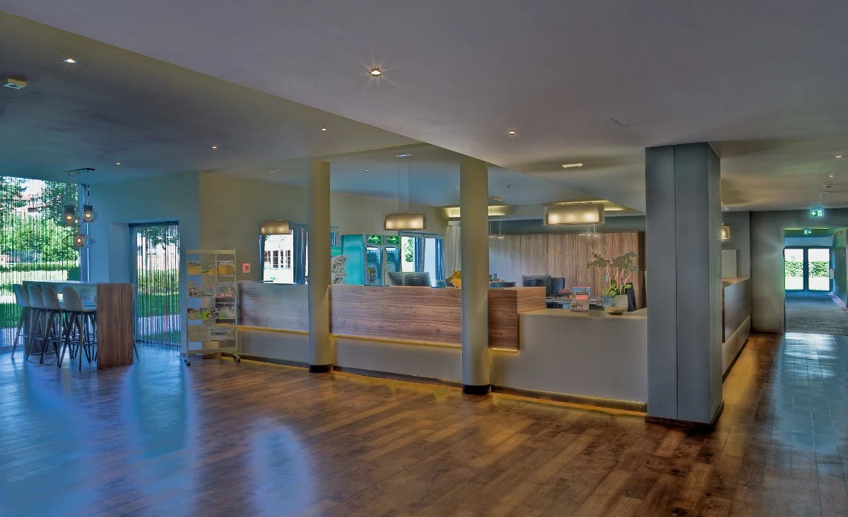 Empfangsbereich eines Hotels mit Holzfußboden, eleganter Empfangstresen und bequemen Sitzgelegenheiten.