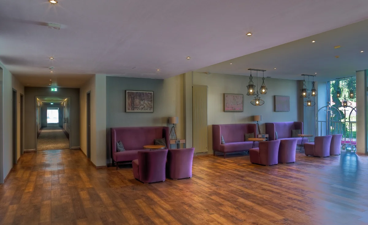 Empfangsbereich eines Hotels, ausgestattet mit lila Stühlen und einem eleganten Holzfußboden.