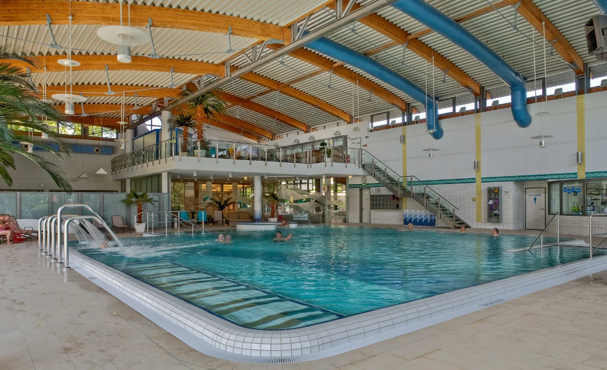 Ein großes Hallenbad mit einem weitläufigen Schwimmbecken und umgebenden Liegen.