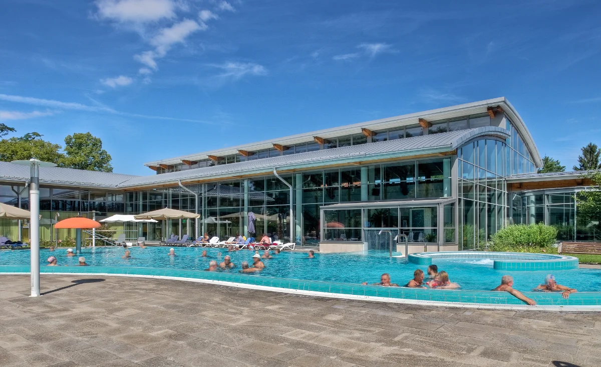 Menschen entspannen sich am Pool eines Resorts unter sonnigem Himmel.