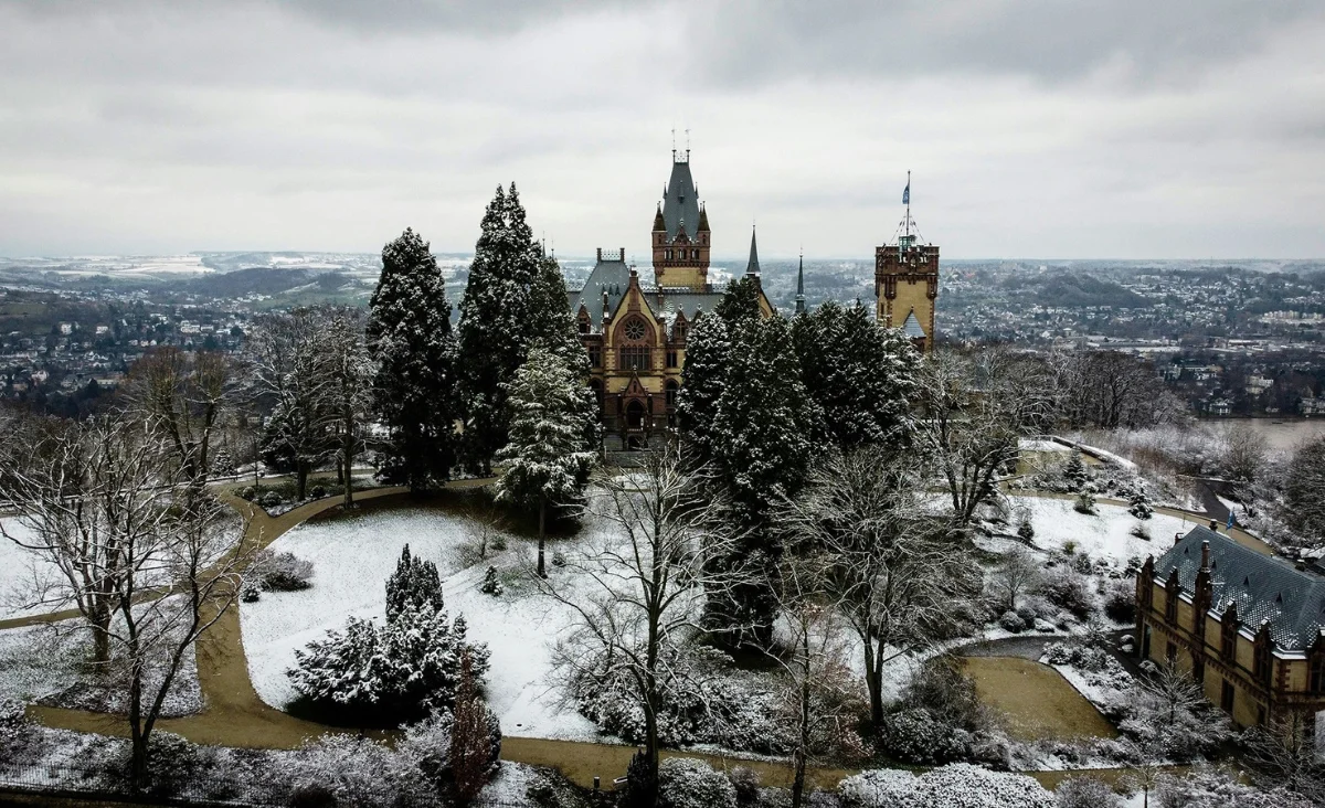 Schloss Drachenburg in Königswinter, umgeben von schneebedeckten Bäumen und einer winterlichen Landschaft
