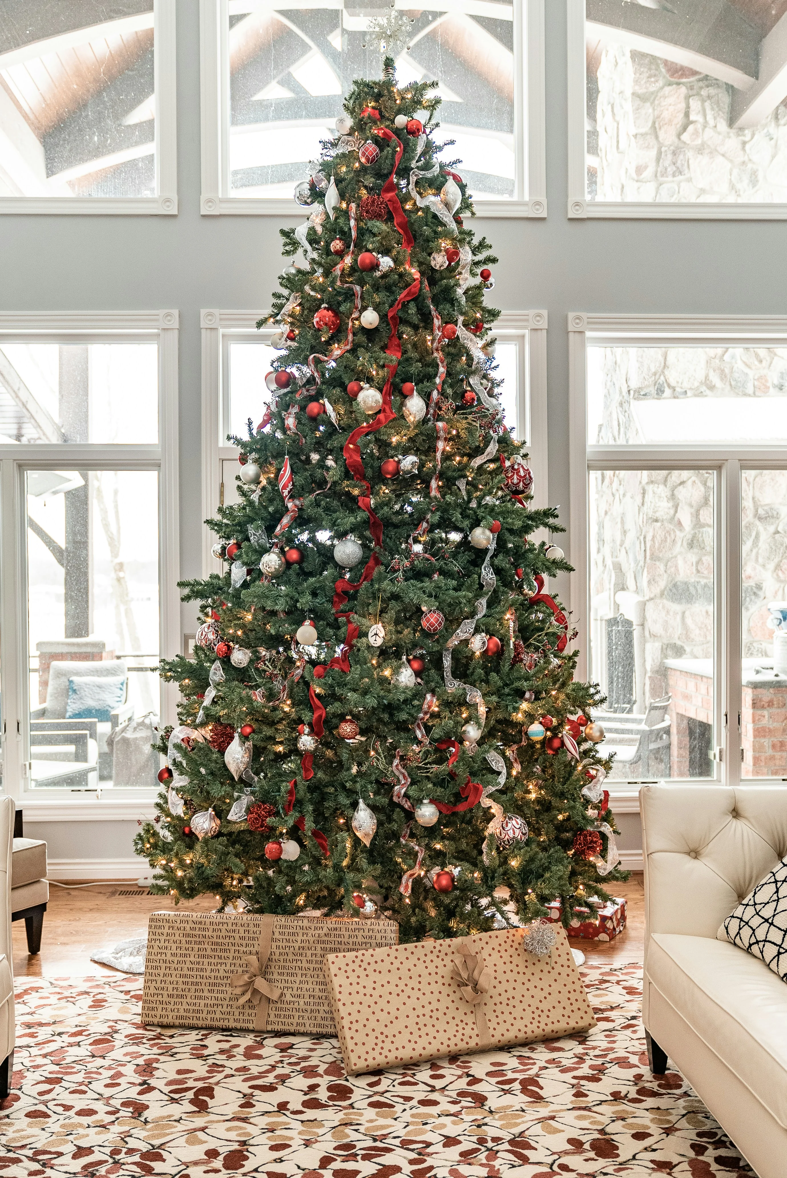 Ein großer Weihnachtsbaum von Tannenparadies Berlin steht in einem Wohnzimmer mit weißen Sofas, dekoriert für die festliche Saison.