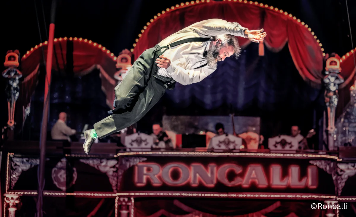 Ein Mann im Anzug führt an einem Zirkuspol im Roncalli Weihnachtscircus Berlin eine beeindruckende Darbietung auf.