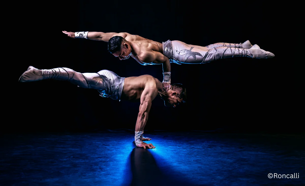 Zwei Männer führen Akrobatik auf einer dunklen Bühne beim Roncalli Weihnachtscircus in Berlin vor.
