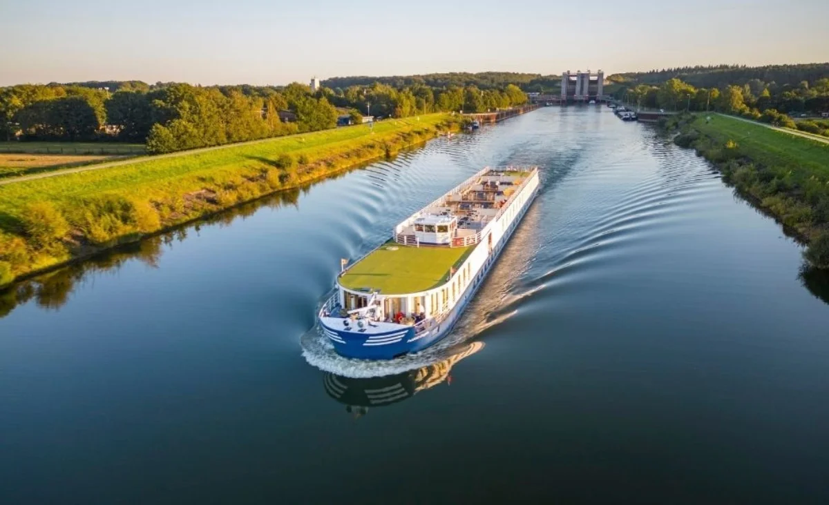 Ein großes blau-weißes Boot-MS Thurgau Chopin - fährt gemächlich einen Fluss entlang, ideal für eine 8-tägige Flusskreuzfahrt für zwei.