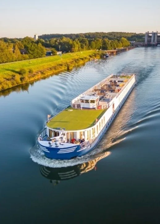 Ein großes blau-weißes Boot-MS Thurgau Chopin - fährt gemächlich einen Fluss entlang, ideal für eine 8-tägige Flusskreuzfahrt für zwei.