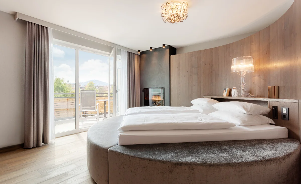 Luxuriöse Suite im Hotel Bodenmaiser Hof mit rundem Doppelbett, Kamin, Holzverkleidung und Balkon mit Panoramablick